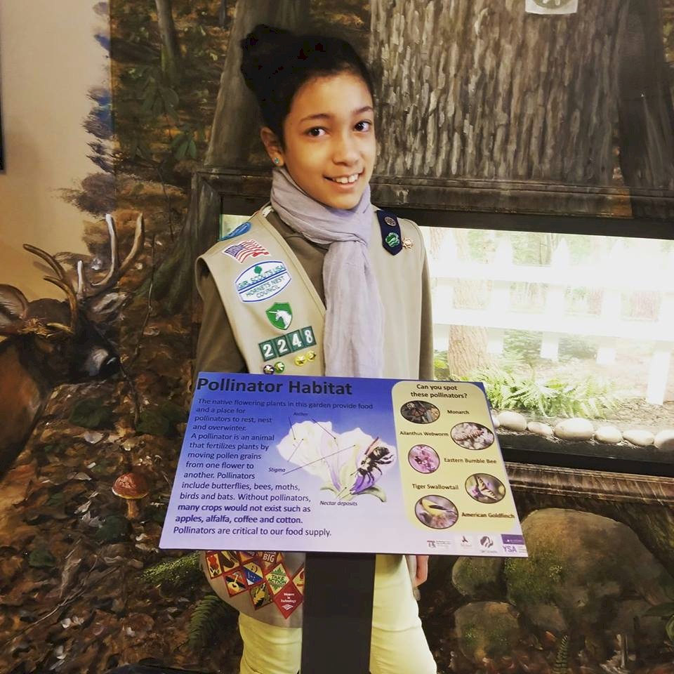 Cadette Girl Scout with donated sign for butterfly garden.
